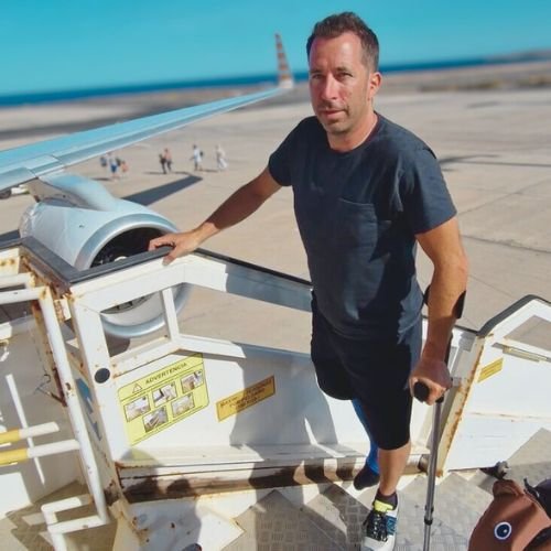 Ich mit Krücken auf der Treppe zum Flugzeug